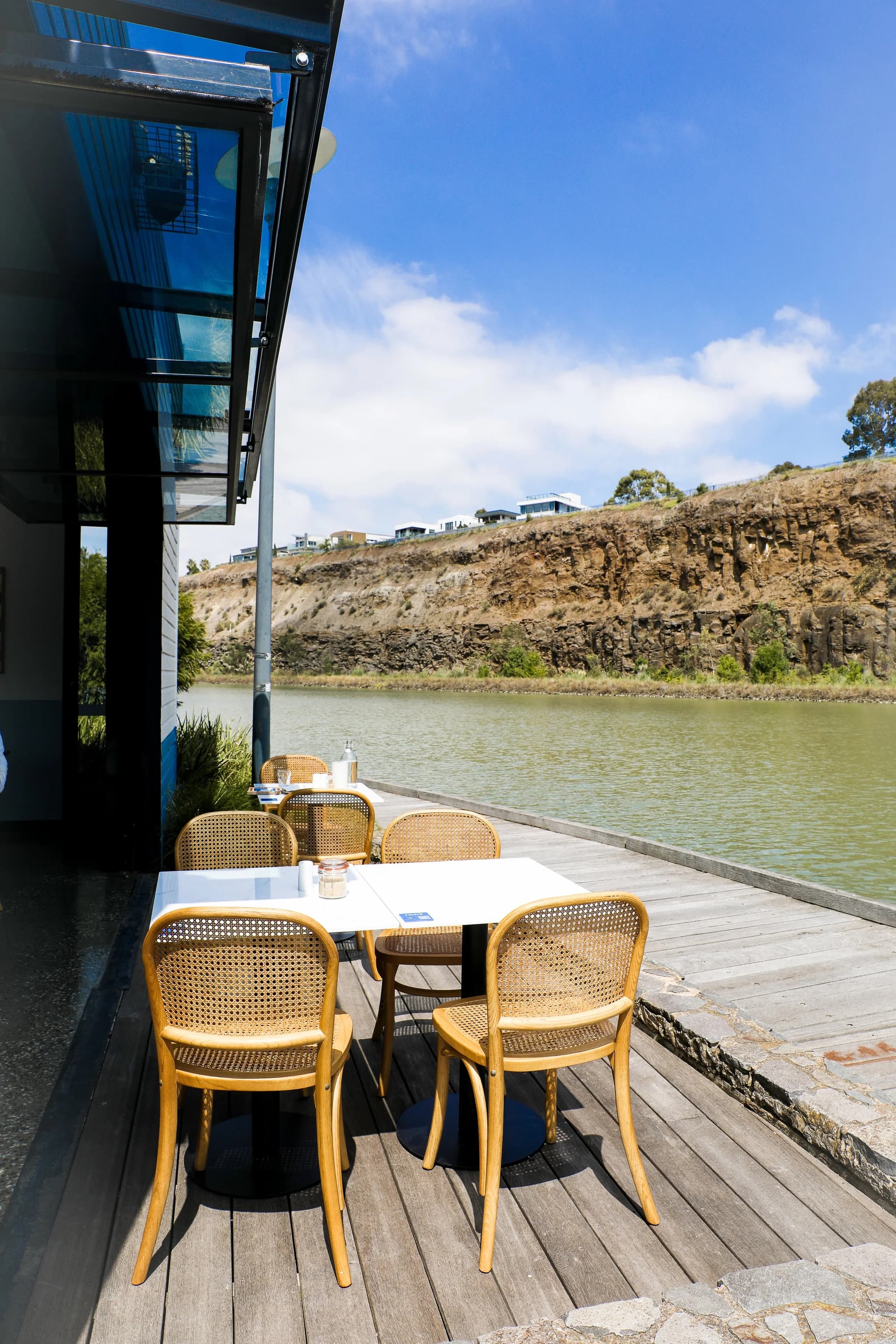 A table on the deck overlooking the lake and cliffs